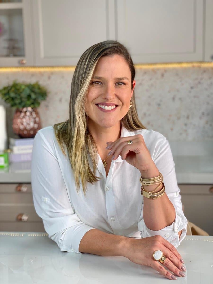 Carla Borges, confeiteira e professora, sorrindo na cozinha do seu ateliê