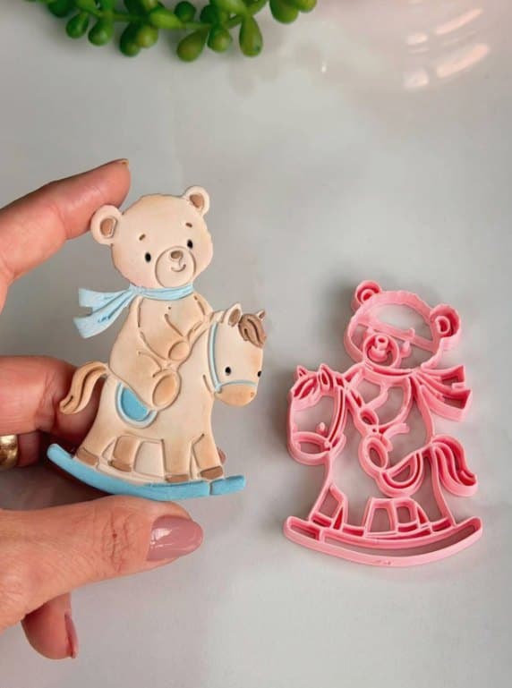 Cortador rosa impresso em 3D ao lado do ursinho no cavalinho de balanço feito em pasta americana